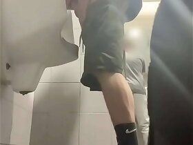 2 boys alongside sneakers having fun at public toilets' urinal